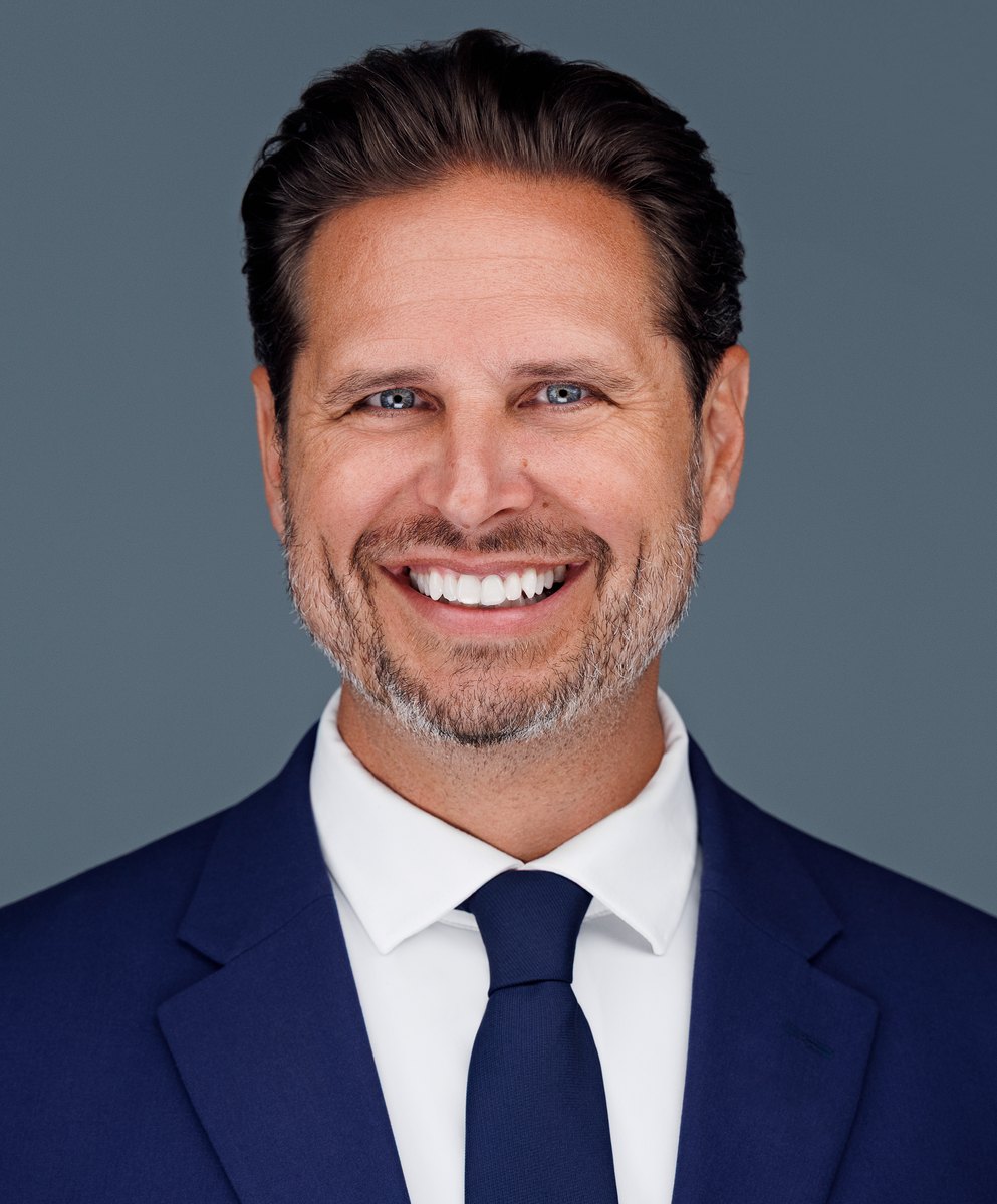 Confident professional headshot on a slate background